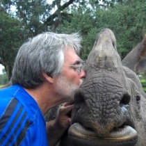 Cal Garbin: Man with thick salt-and-pepper hair kissing a rhinoceros.