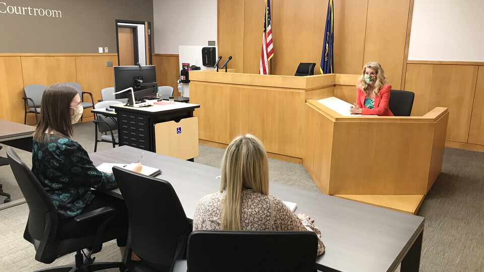 Photo Credit: Michelle Paxton, director of the Children's Justice Clinic, talks with two student attorneys in the Judge Donald R. and Janice C. Ross Courtroom in the College of Law. Clinic student attorneys practice with Paxton before going to court.