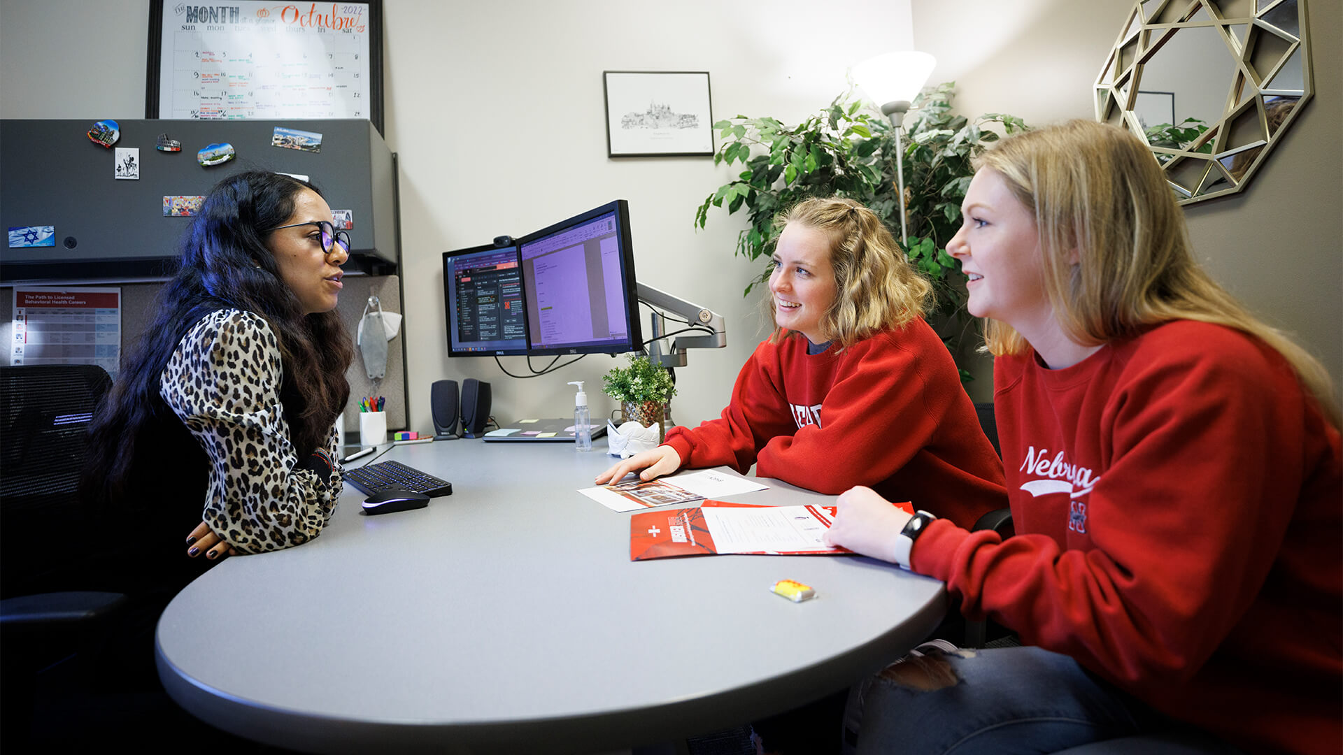 Students meet with adviser around a curved desk.